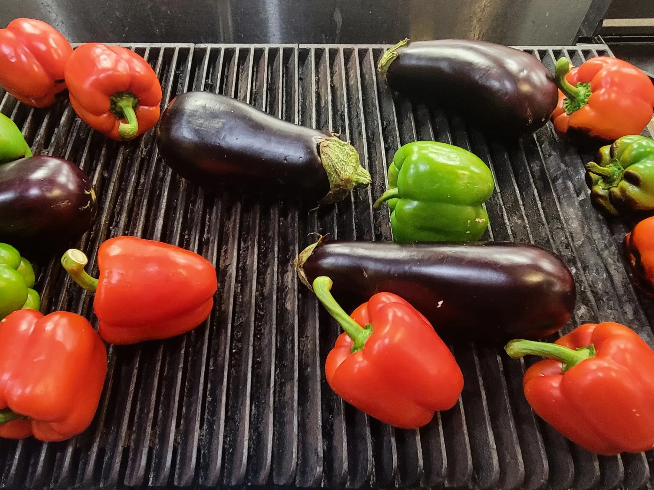 Red peppers, green peppers, and eggplants on a grill.