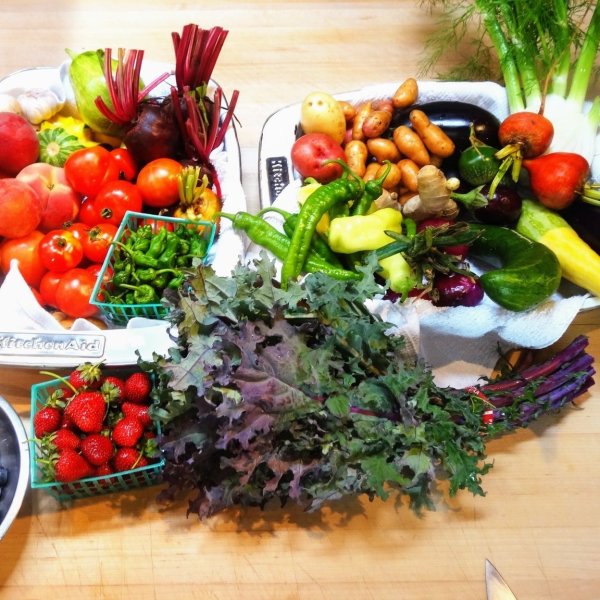 a wooden table topped with lots of fresh fruit and vegetables on display