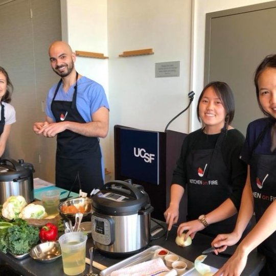 a group of people standing in a kitchen preparing food